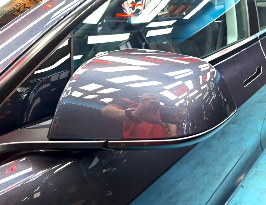 Coated grey side mirror cap reflecting the workshop.