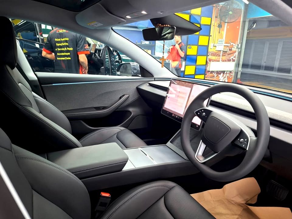 Interior view of the black seats, steering wheel and centre screen.