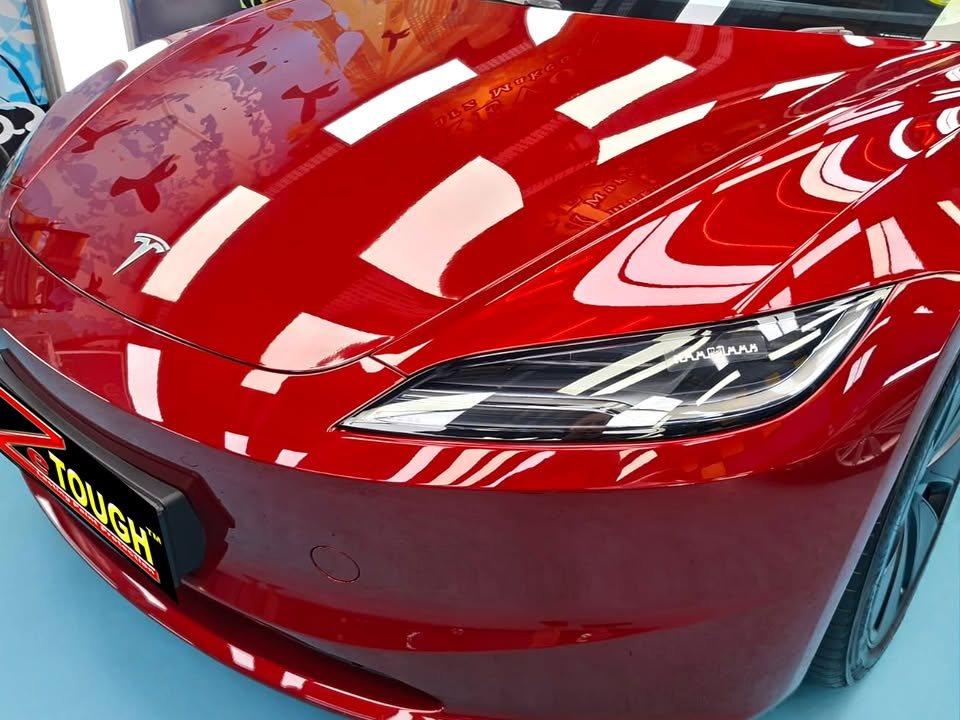 Close-up of the red bonnet and front bumper with light reflections across the paint.