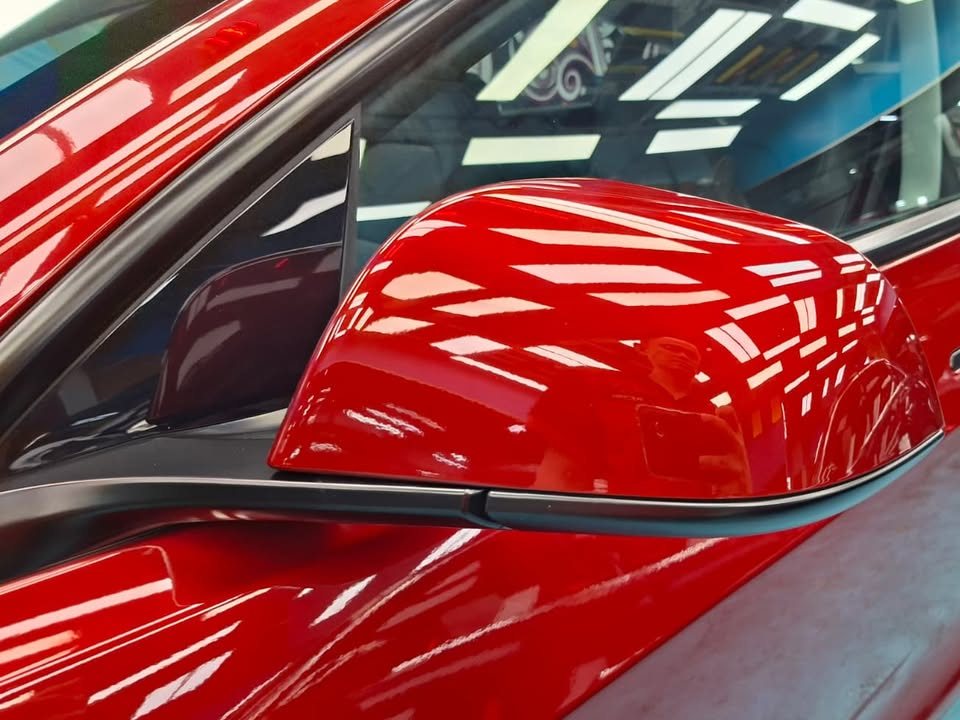 The red wing mirror cap with workshop lights reflected in it.