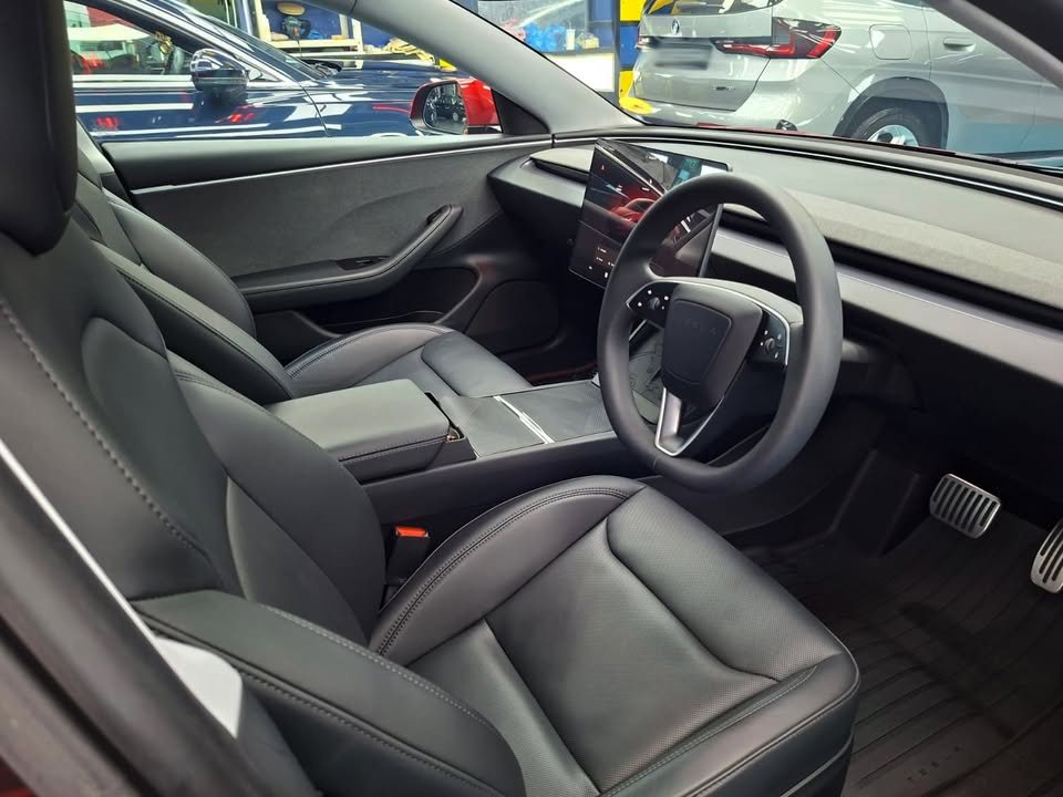 Interior view of the black seats, steering wheel and centre screen.