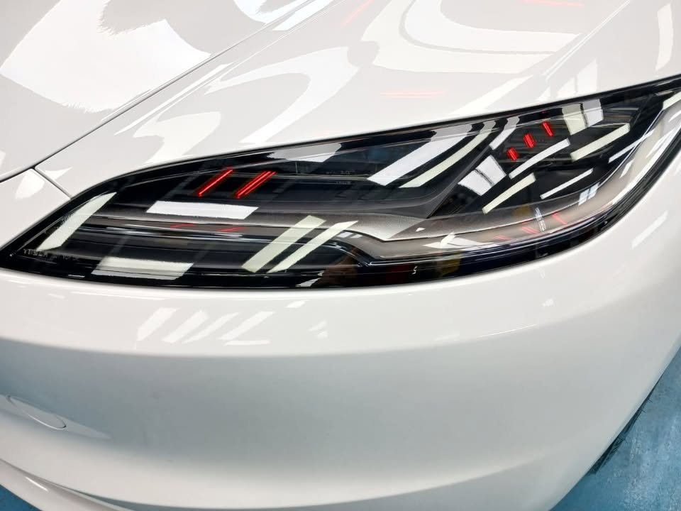 Close-up of the Model 3's headlamp set into the white front bumper.