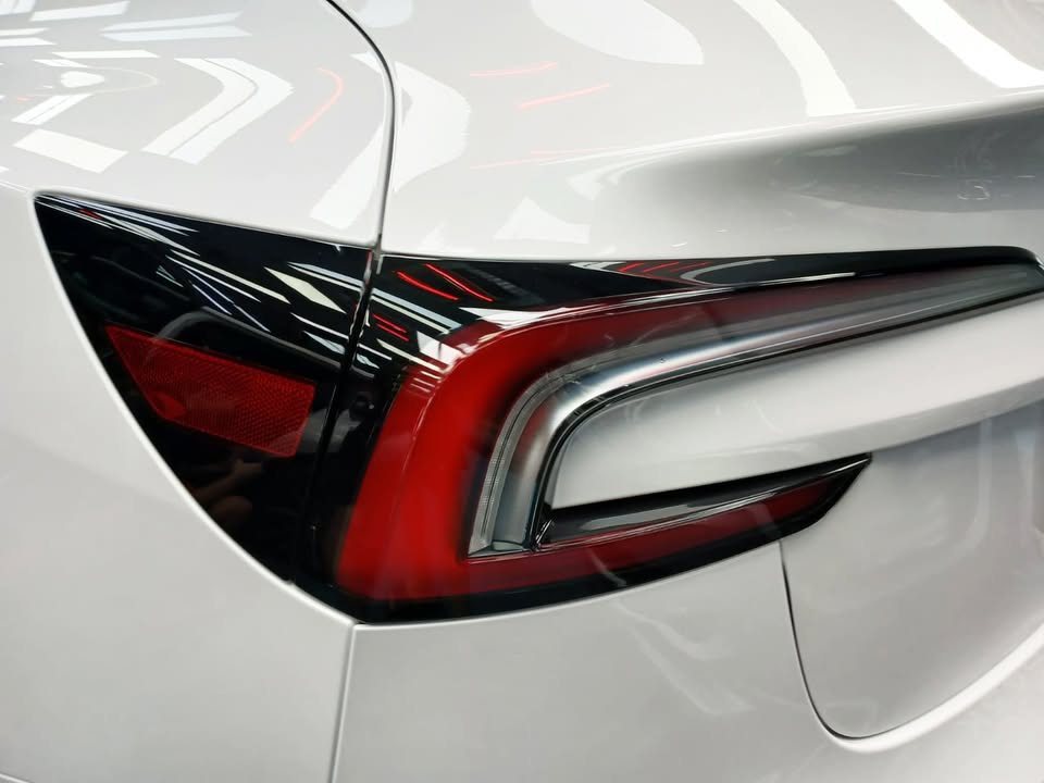 Close-up of the red tail lamp on the white rear quarter of the Model 3.