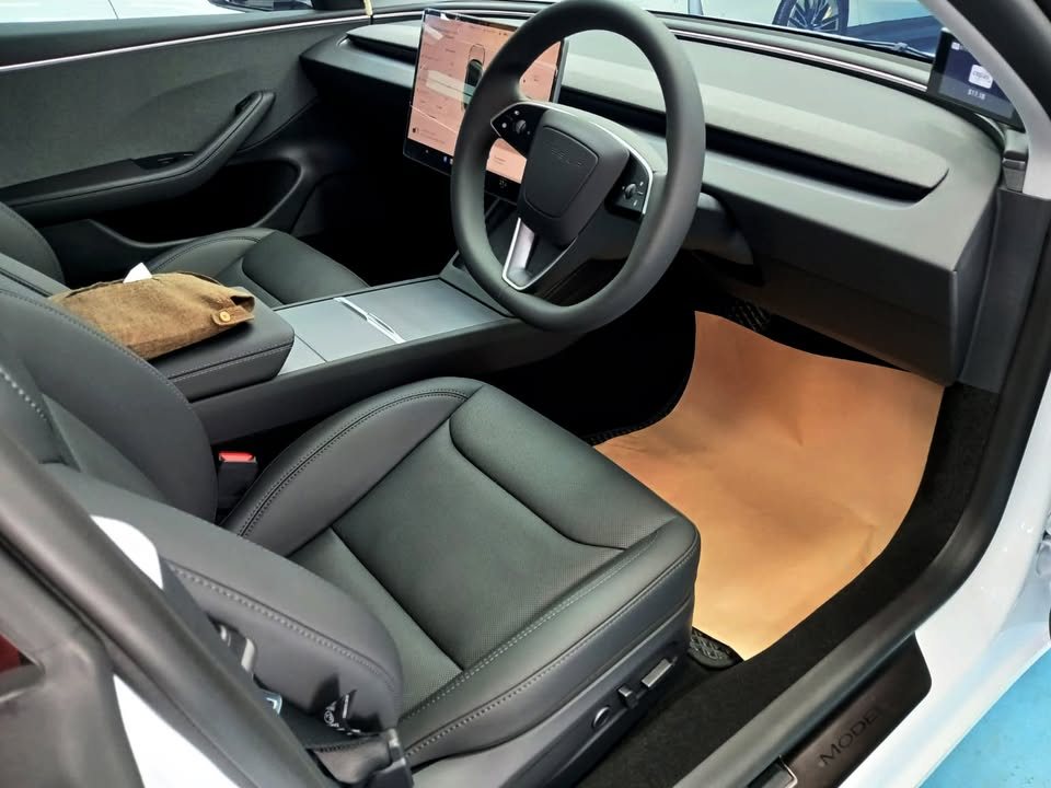 Black front seats, steering wheel and centre screen inside the Tesla Model 3.