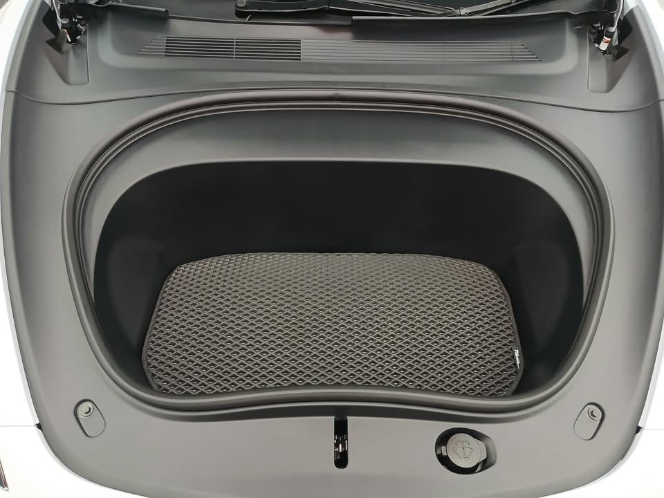 Front trunk of the Tesla Model 3 with a grey mat inside.