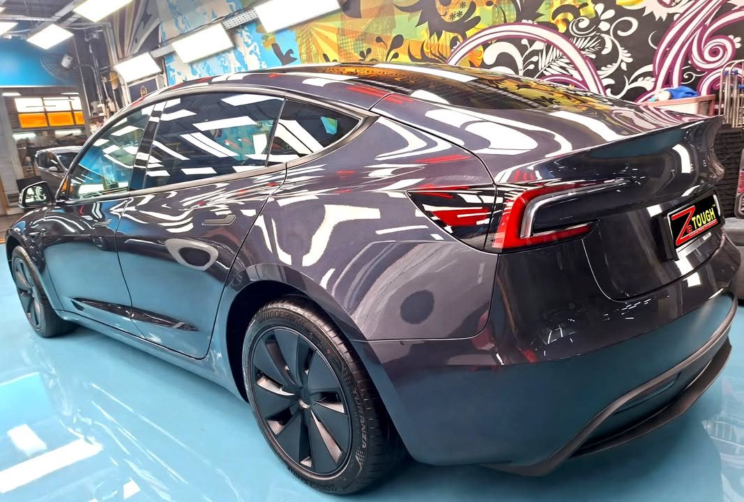 Rear three-quarter view of the Tesla Model 3 showing the tail lamps and wheels.