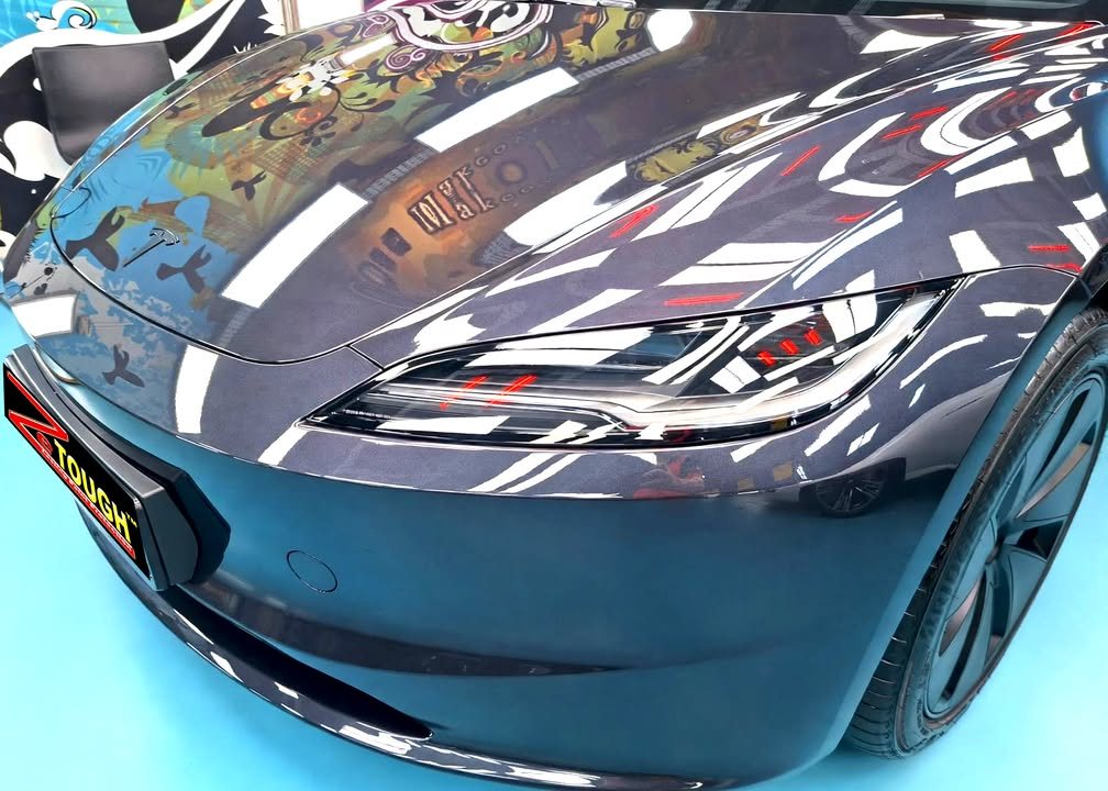 Close view of the Tesla's front bumper and bonnet with sharp light reflections.