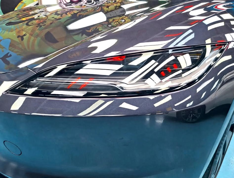Headlamp and front wing of the Tesla Model 3 up close.