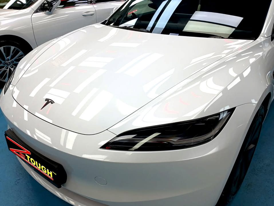 Close-up of the white bonnet and front bumper with the Tesla badge.