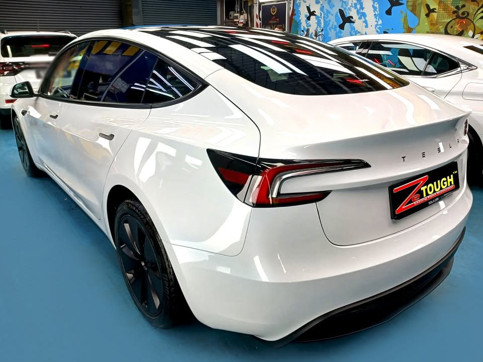 Rear three-quarter view of the white Tesla Model 3 with black wheel covers.