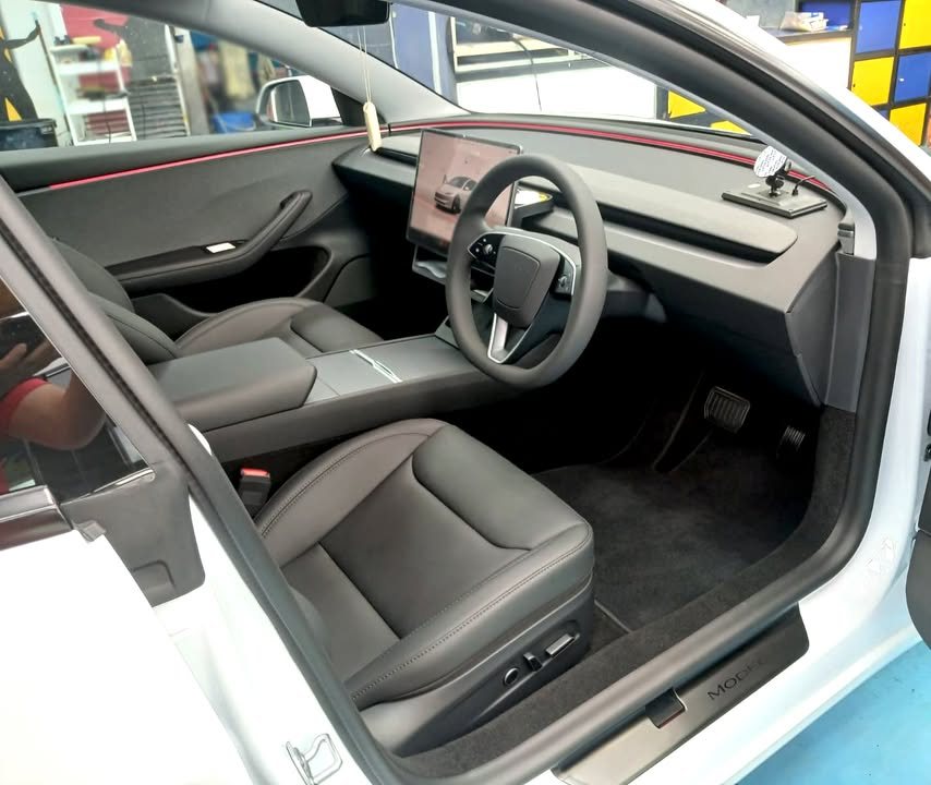 Interior view through the open door showing the black seats and steering wheel.