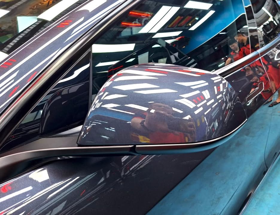Dark grey door mirror on the Tesla Model 3 with sharp reflections.