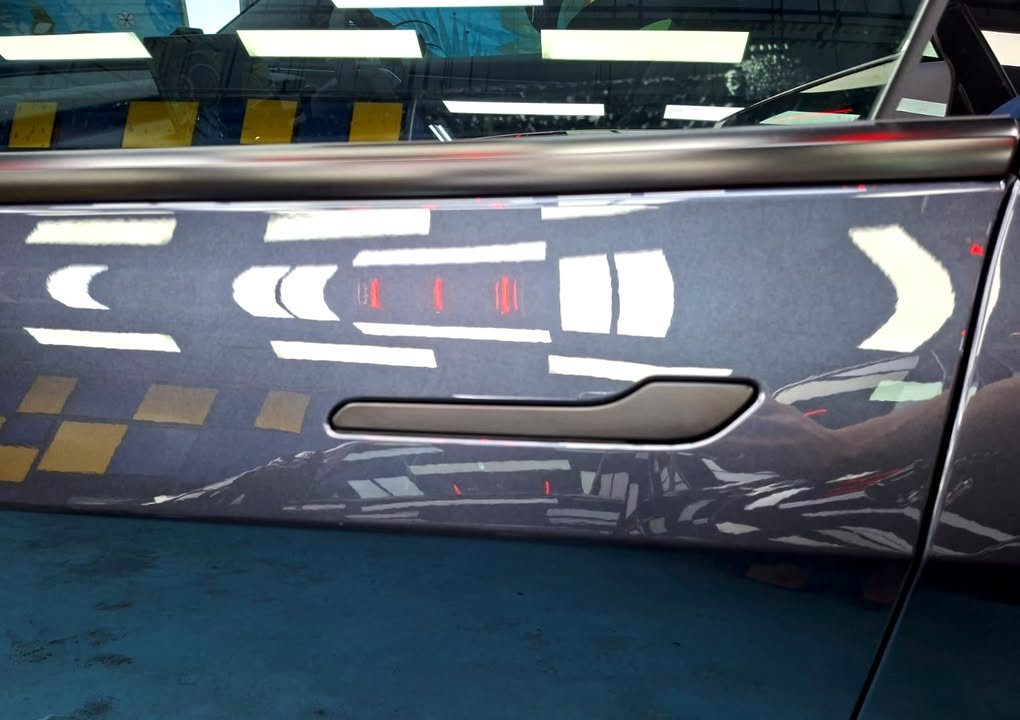 Flush door handle on the dark grey door panel of the Model 3.
