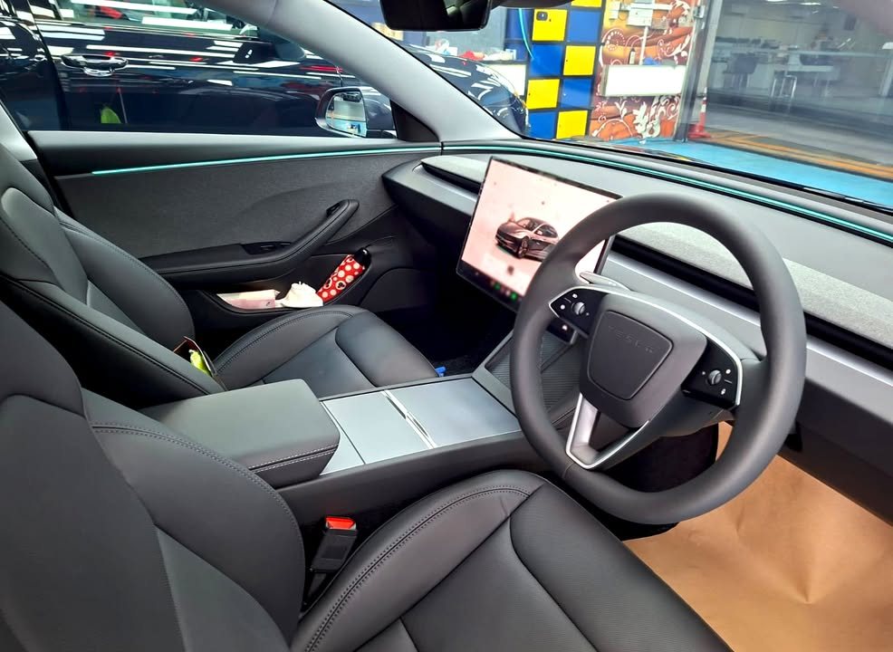 Black front seats, steering wheel and centre screen inside the Tesla Model 3.