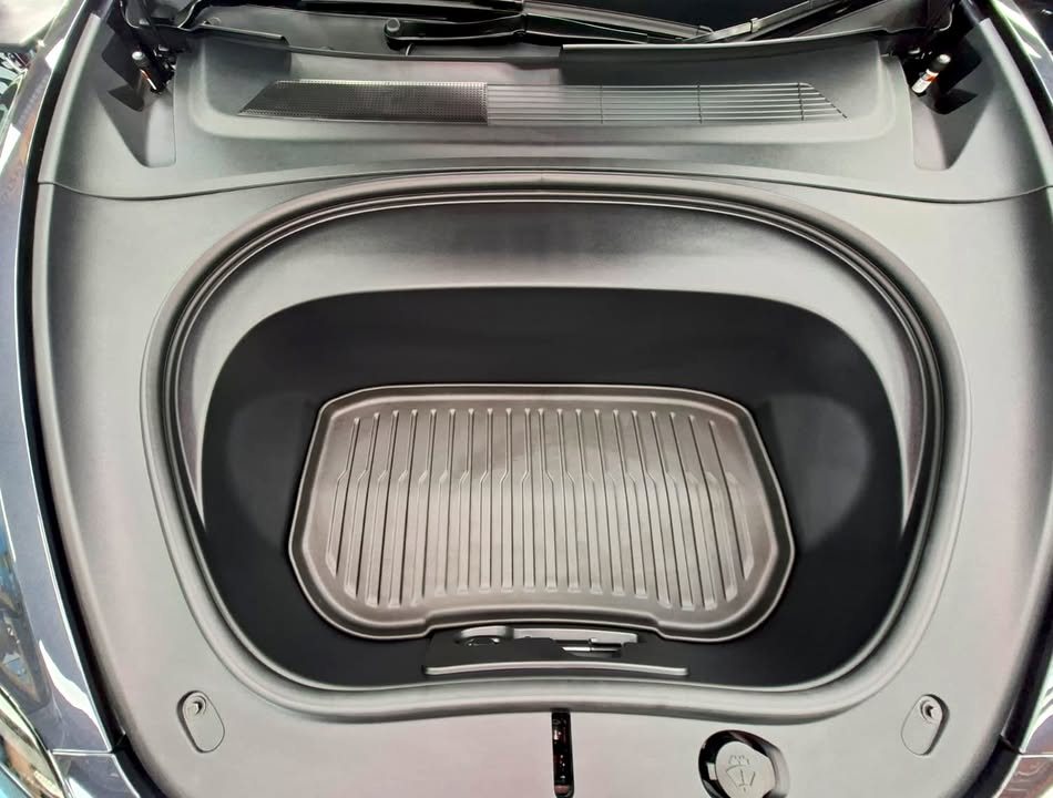 Front trunk of the Tesla Model 3 with a grey mat.