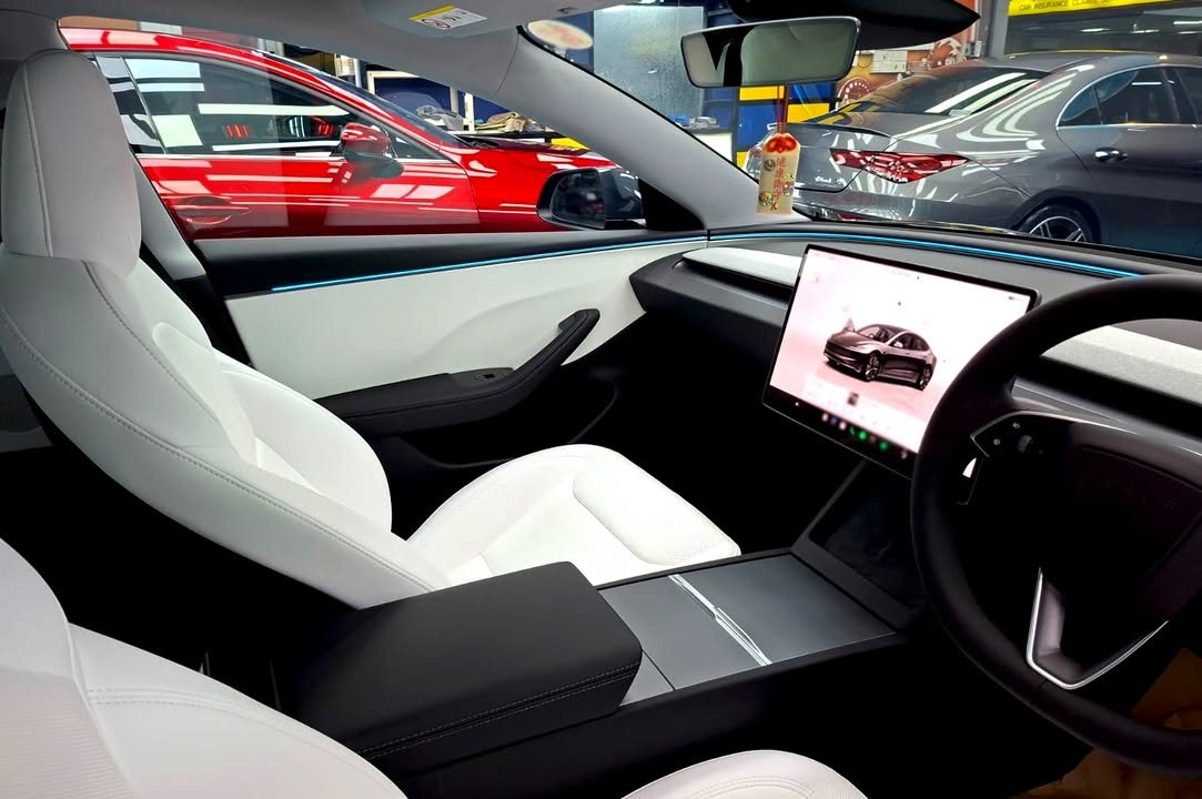 White seats and centre screen inside the Tesla Model 3.