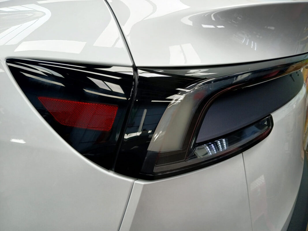 The coated bonnet of the Tesla Model Y under workshop lighting.