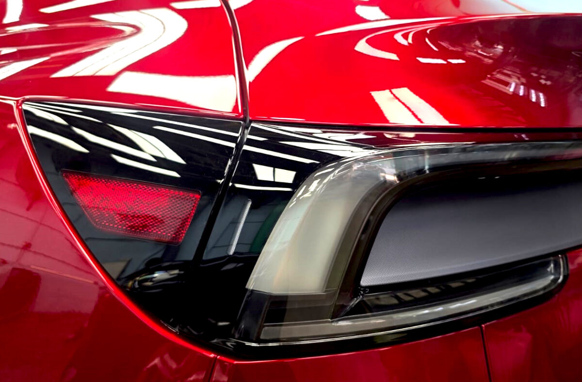 The coated bonnet of the Tesla Model Y under workshop lighting.
