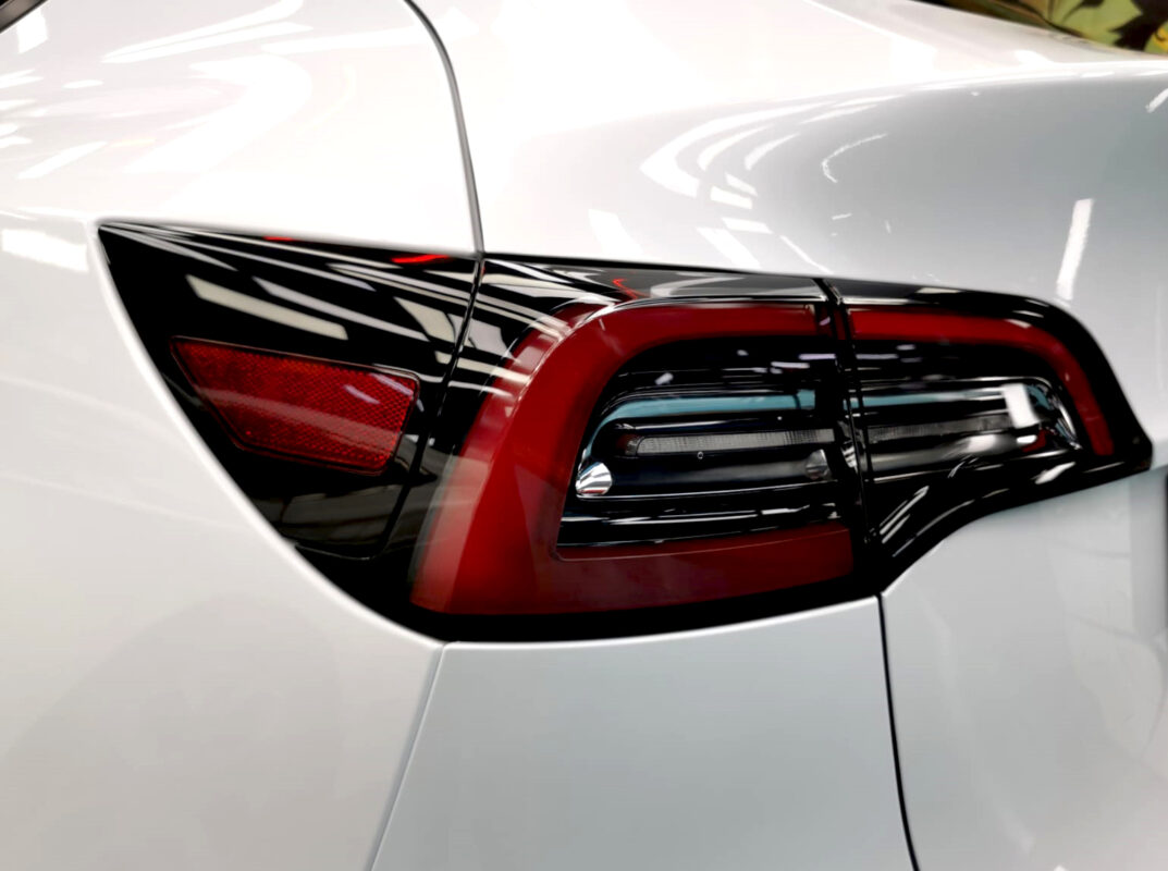 The coated bonnet of the Tesla Model Y under workshop lighting.