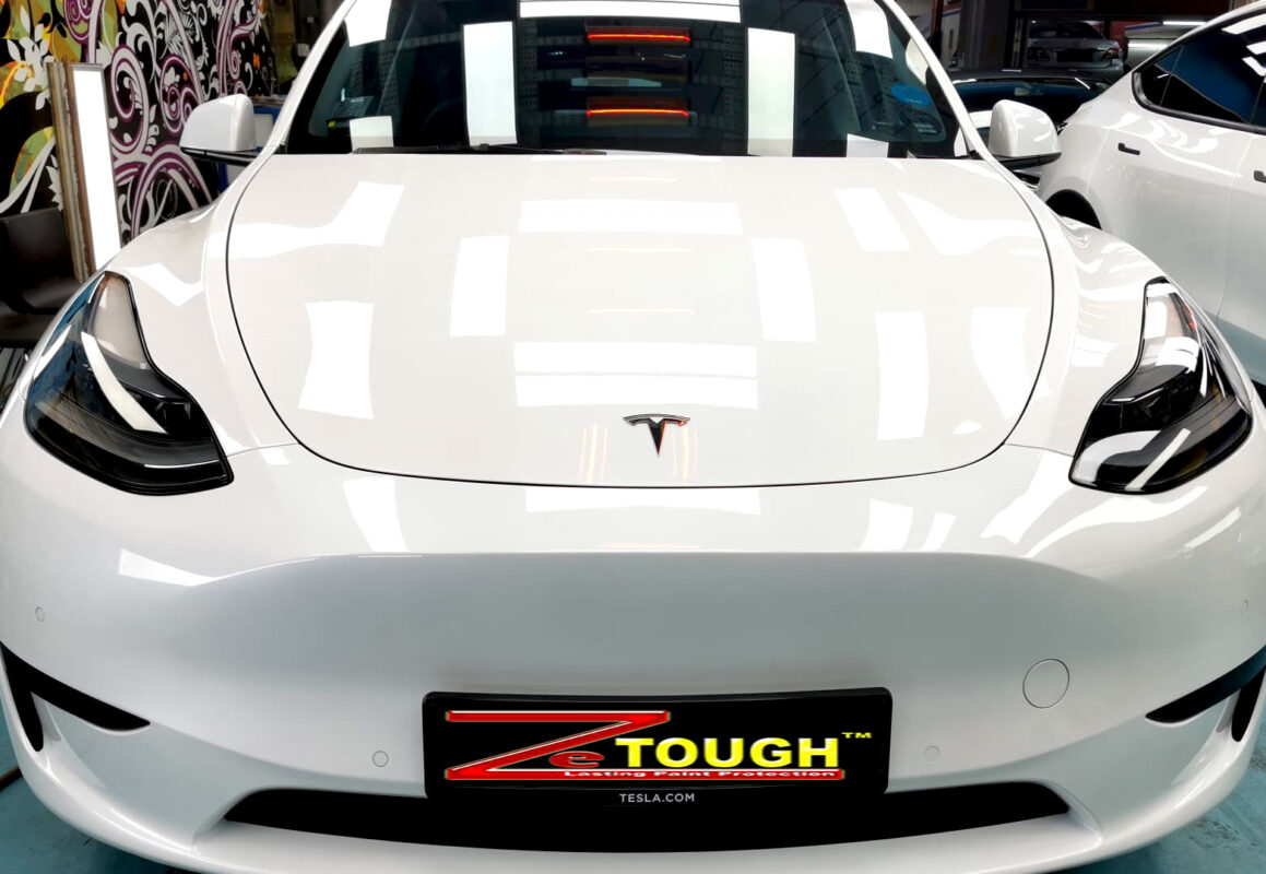 The Tesla Model Y's coated paintwork under workshop lighting.