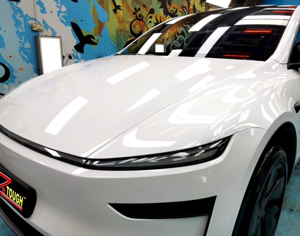The Tesla Model Y's coated paintwork under workshop lighting.