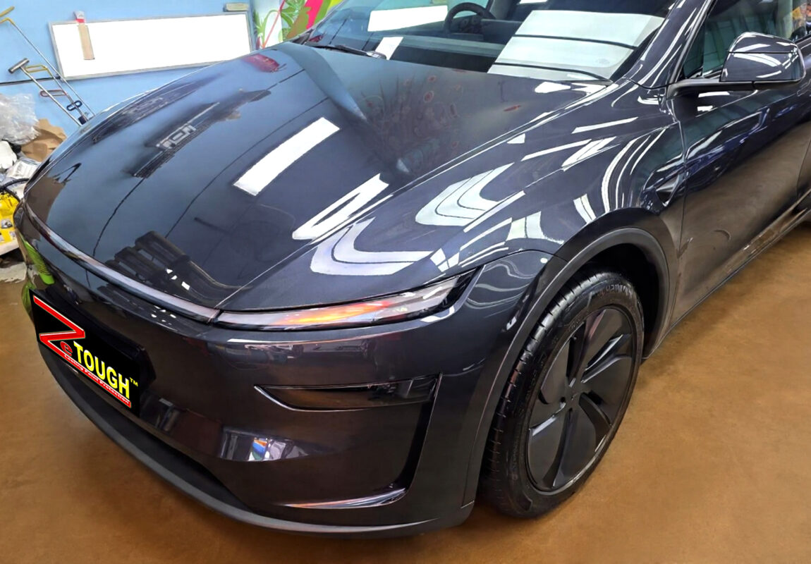 The Tesla Model Y's coated paintwork under workshop lighting.