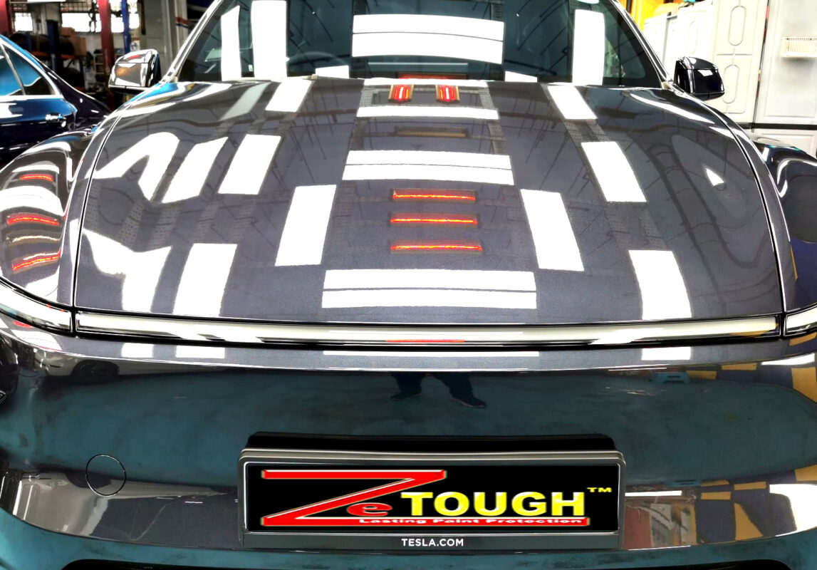 The Tesla Model Y's coated paintwork under workshop lighting.