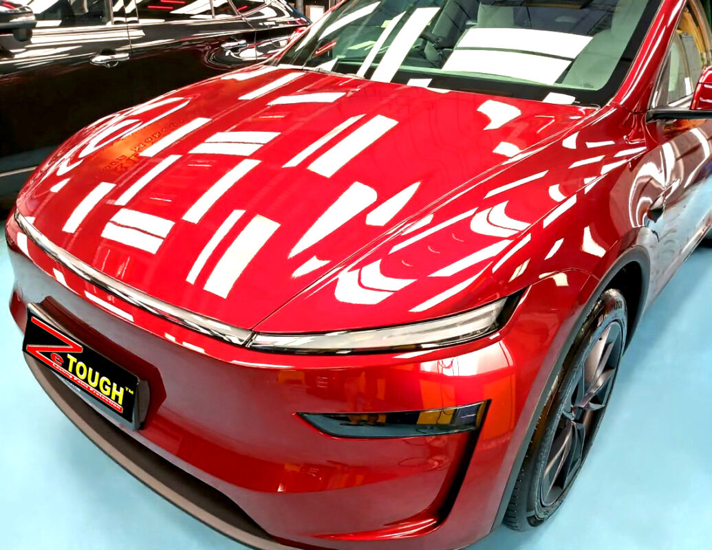 The Tesla Model Y's coated paintwork under workshop lighting.