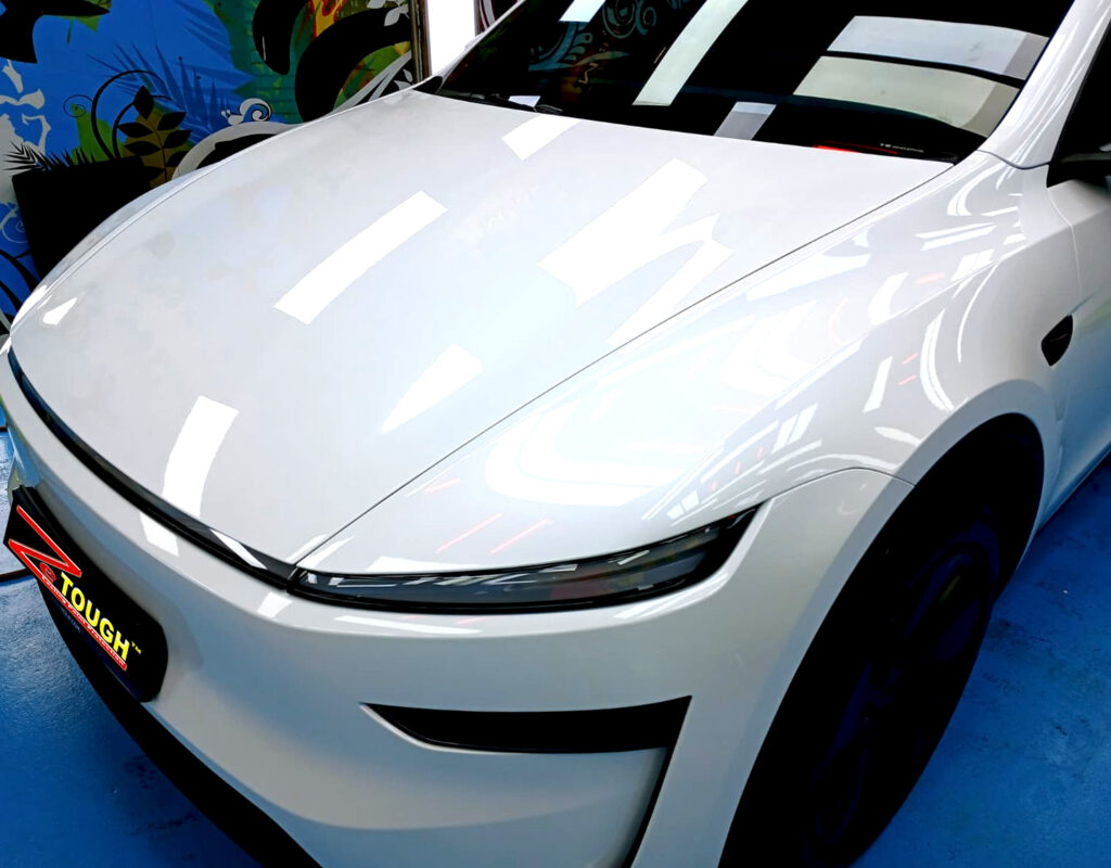 The Tesla Model Y's coated paintwork under workshop lighting.