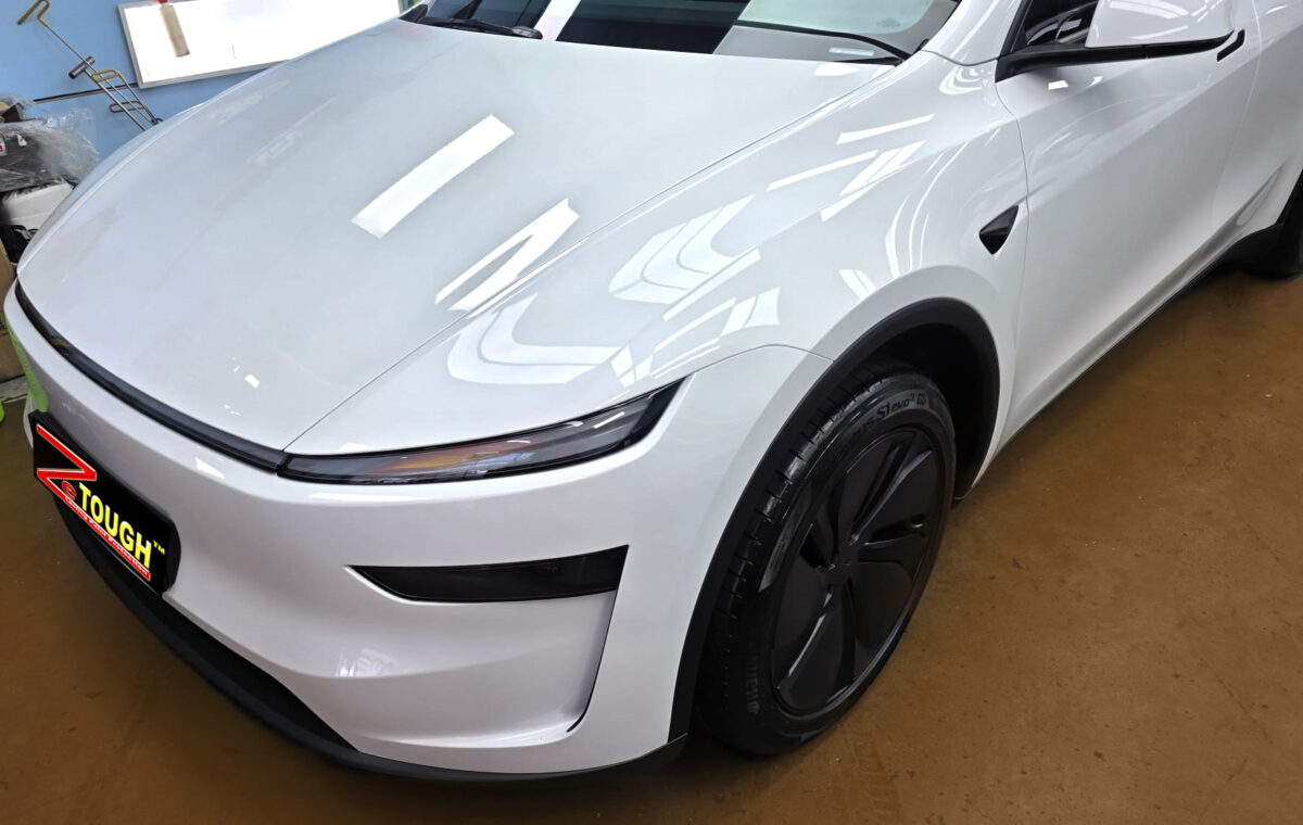 The Tesla Model Y's coated paintwork under workshop lighting.