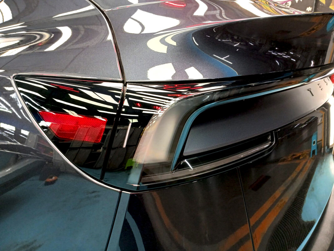 The coated bonnet of the Tesla Model Y under workshop lighting.
