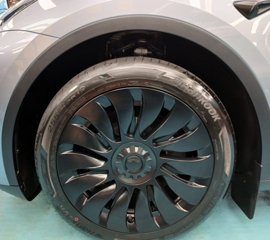 The coated bonnet of the Tesla Model Y under workshop lighting.
