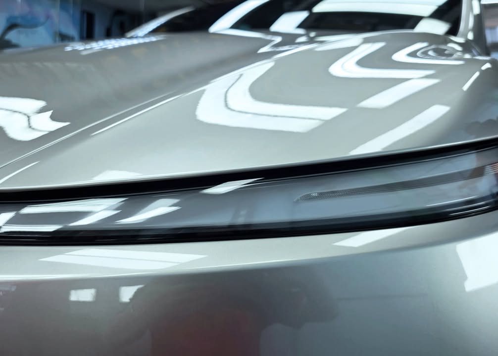 Close-up of the bonnet edge and light bar with workshop lights reflected in the silver paint.