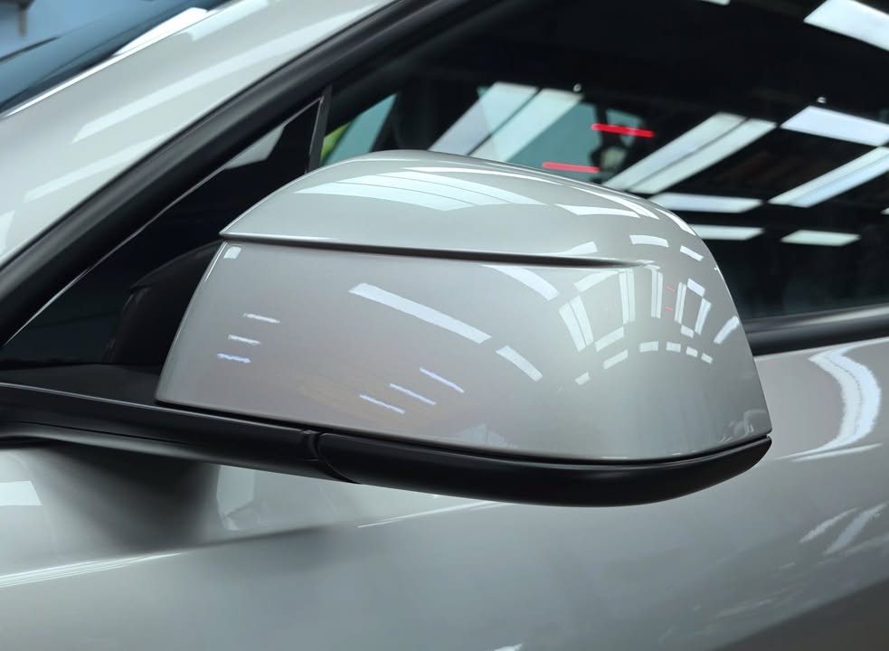 Silver side mirror cap reflecting the workshop lights.
