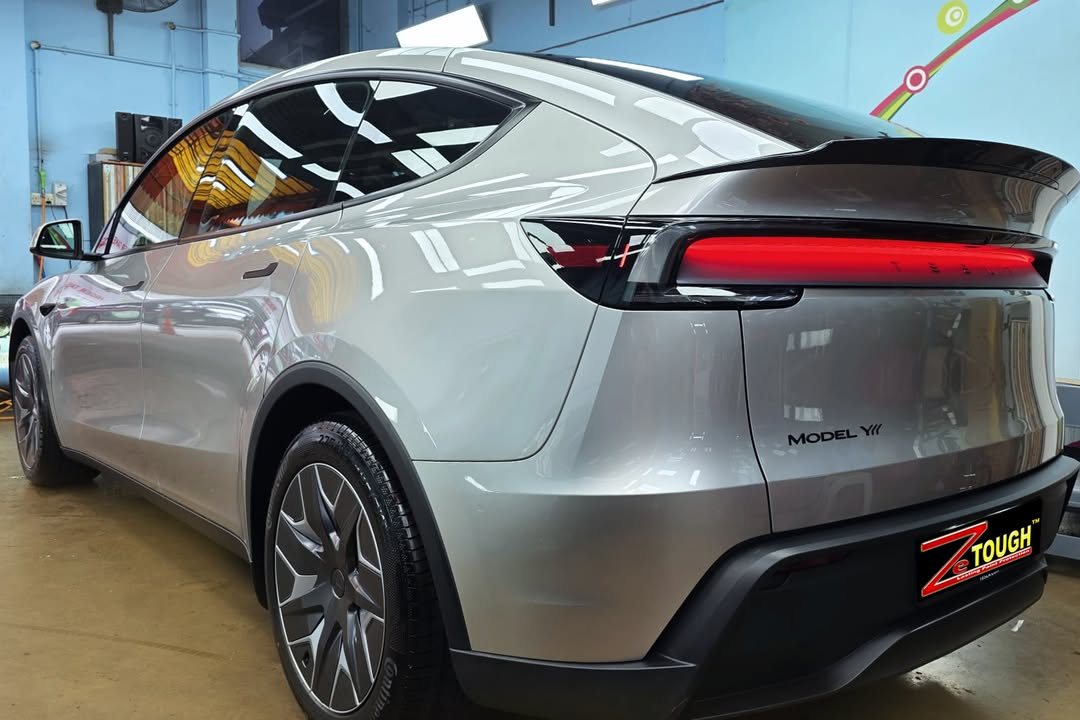Rear three-quarter view of the silver Model Y L with its full-width red tail light.