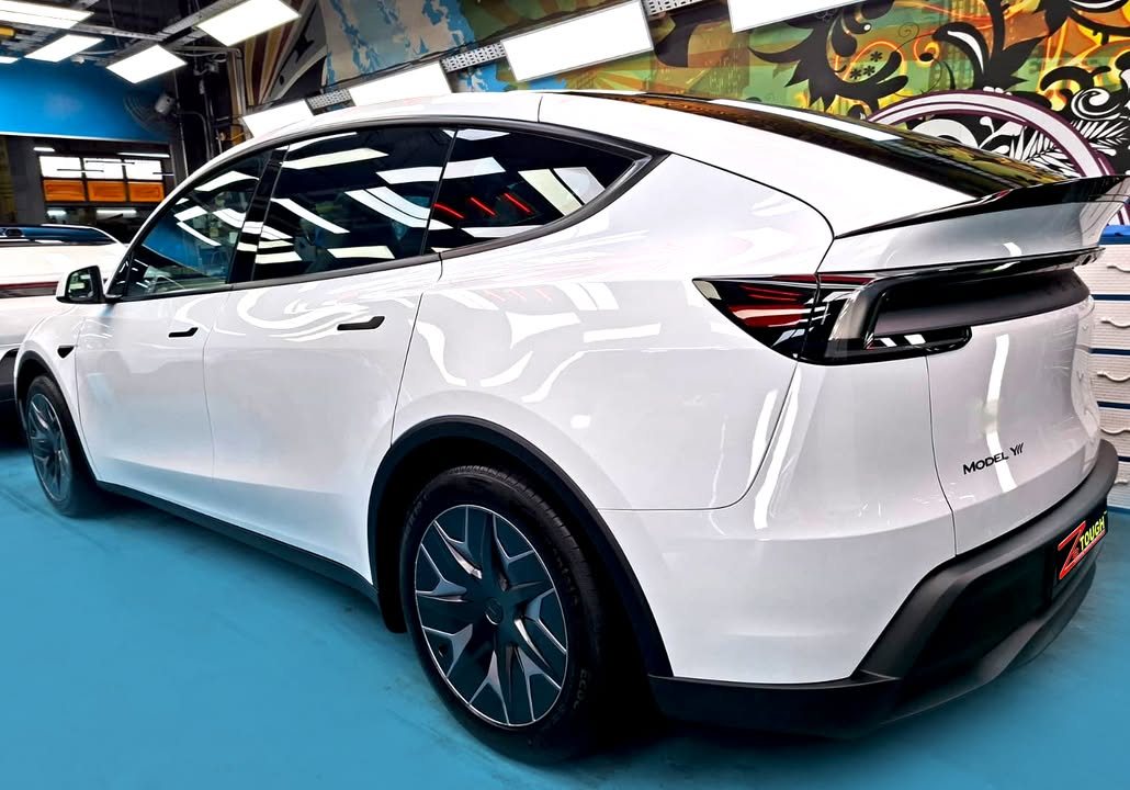Rear three-quarter view of the white Tesla Model Y L in the workshop.