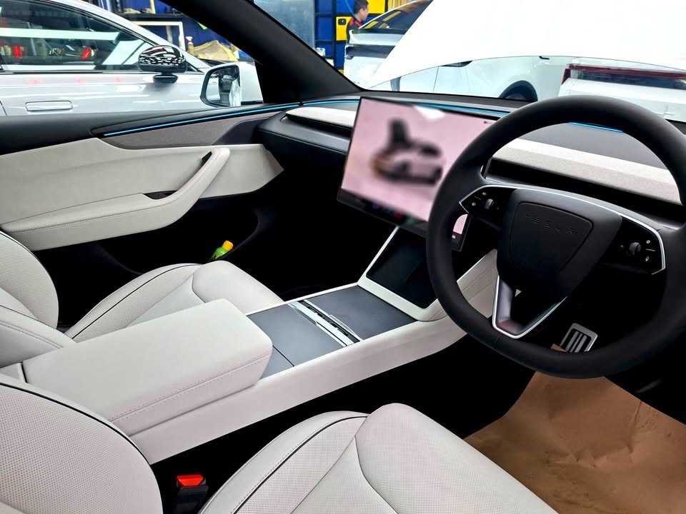 Light grey seats, steering wheel and centre screen inside the Tesla Model Y L.