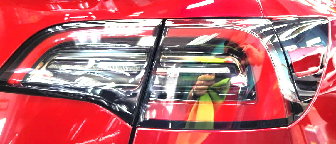 The coated bonnet of the Tesla Model Y under workshop lighting.