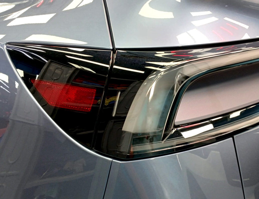 The coated bonnet of the Tesla Model Y under workshop lighting.