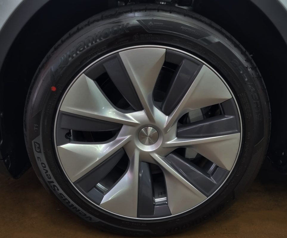 The coated bonnet of the Tesla Model Y under workshop lighting.