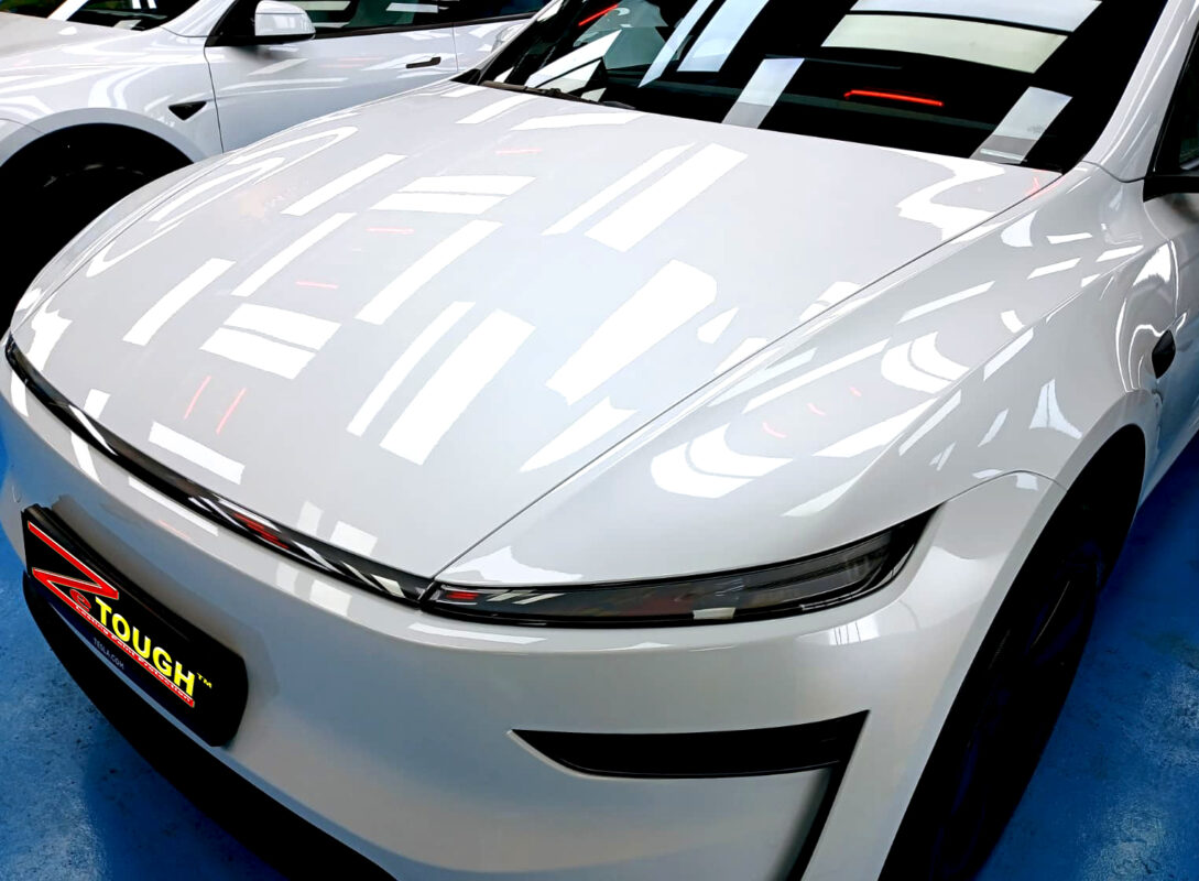 The Tesla Model Y's coated paintwork under workshop lighting.
