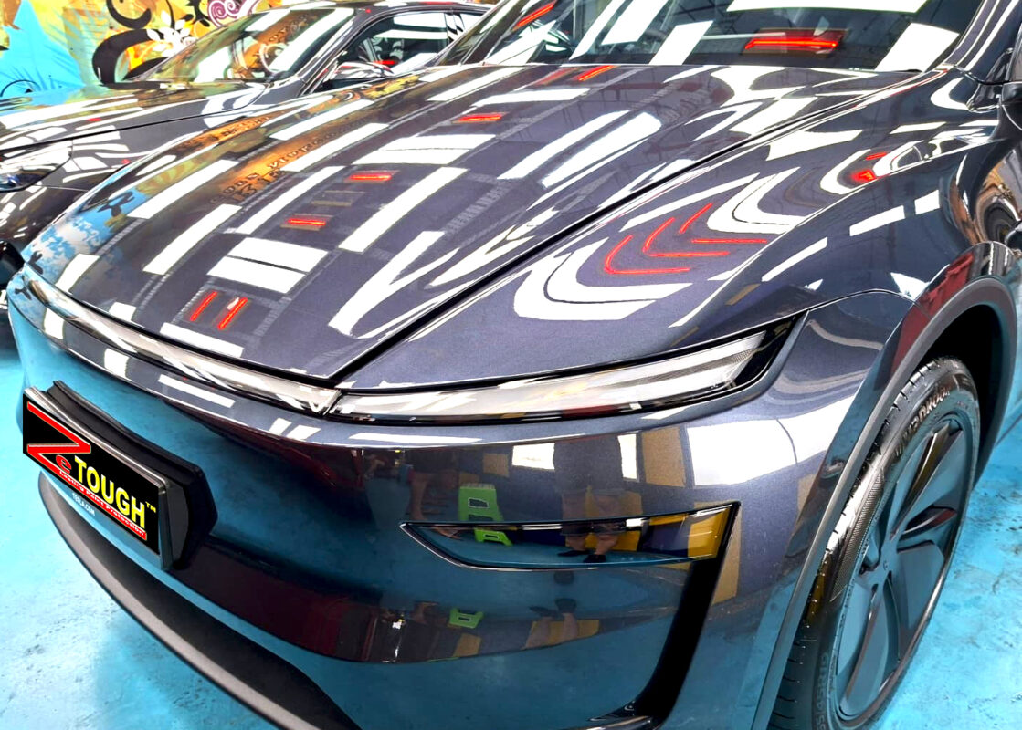 The Tesla Model Y's coated paintwork under workshop lighting.