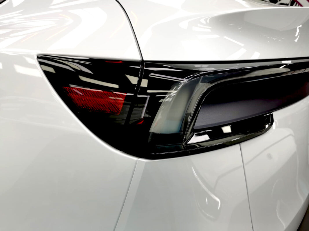 The coated bonnet of the Tesla Model Y under workshop lighting.