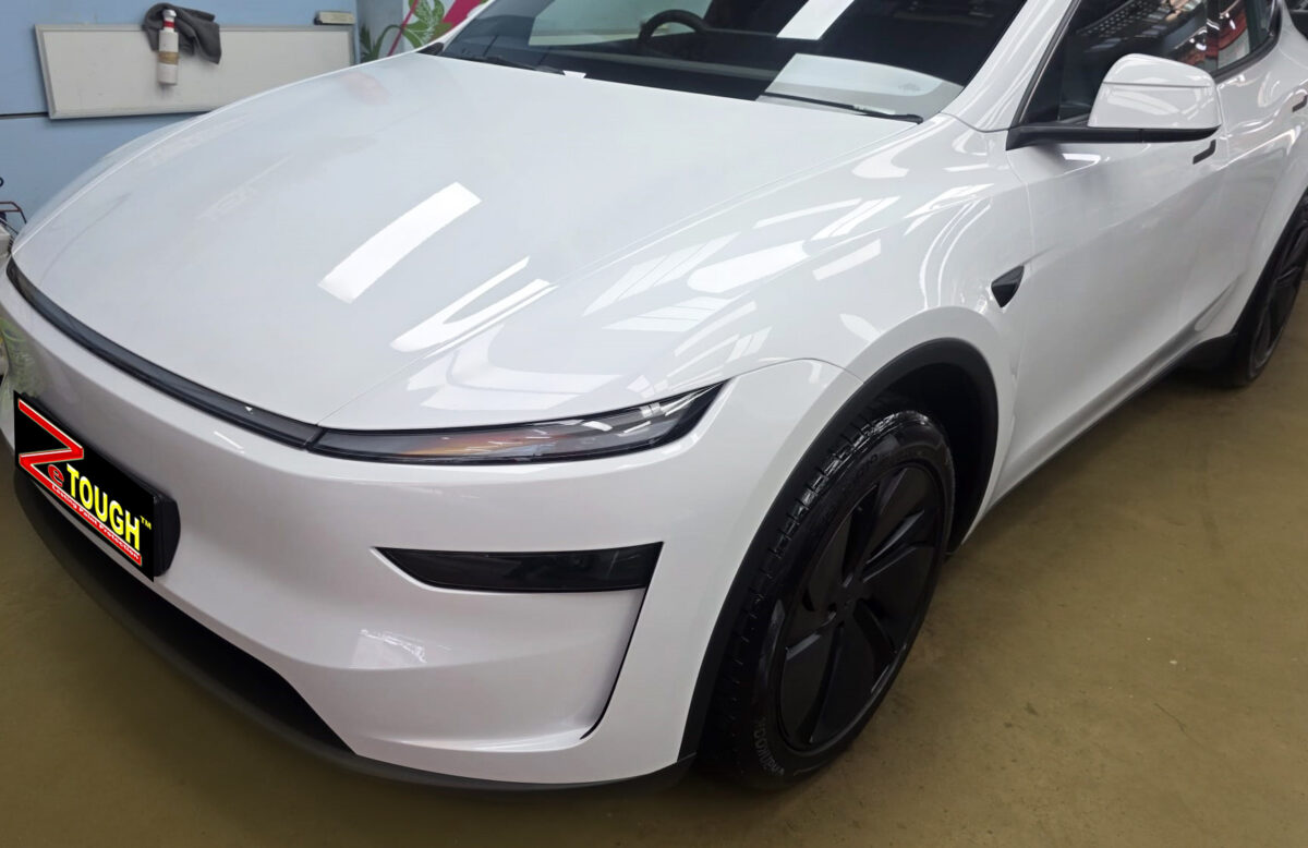 The Tesla Model Y's coated paintwork under workshop lighting.