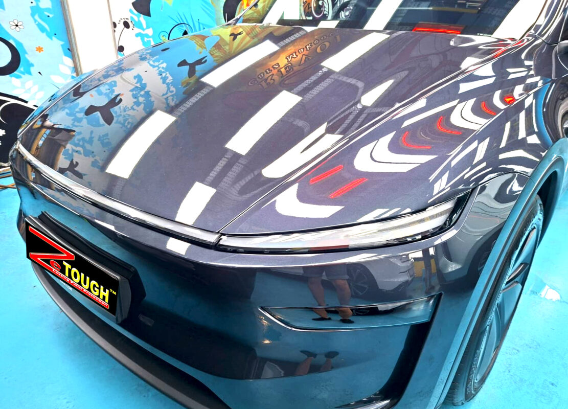 The Tesla Model Y's coated paintwork under workshop lighting.