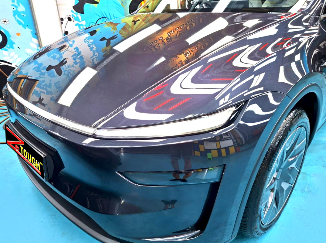 The Tesla Model Y's coated paintwork under workshop lighting.
