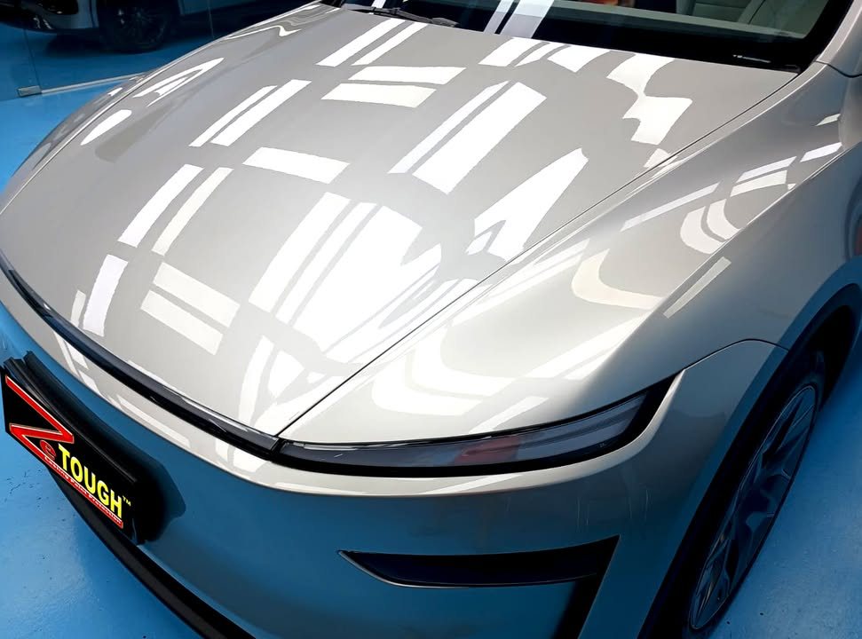 Close-up of the silver bonnet with ceiling lights reflected in the paint.