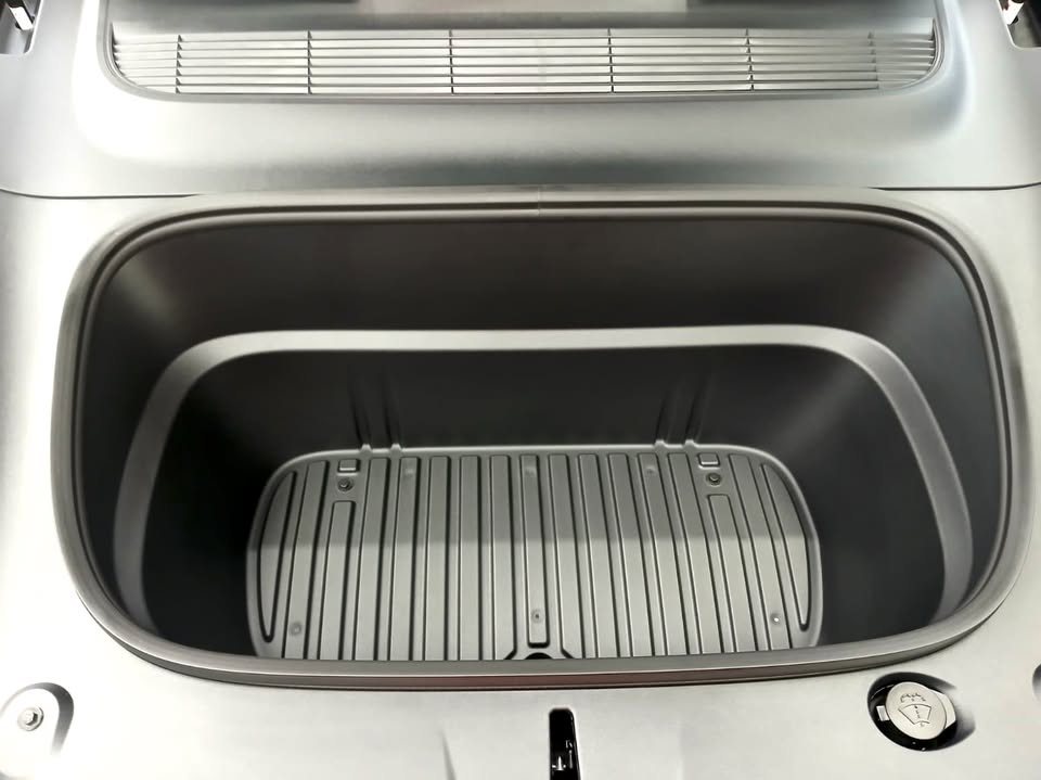 The front storage compartment with a ribbed grey mat.