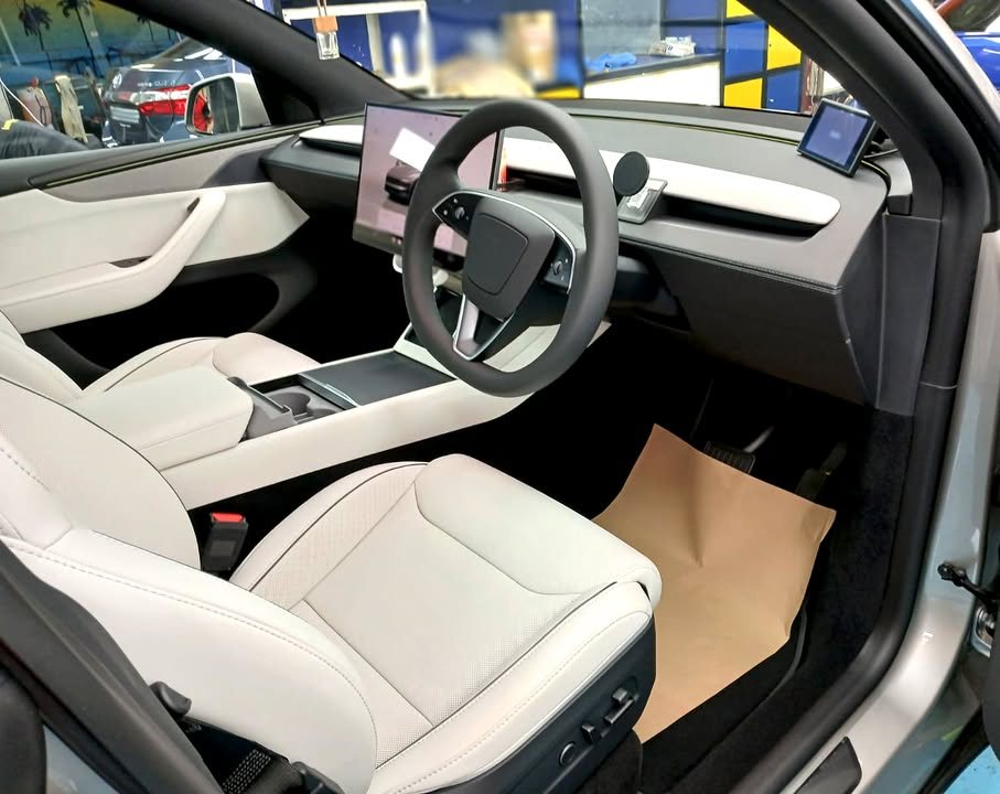 Interior view of the light-coloured seats, steering wheel and centre screen.