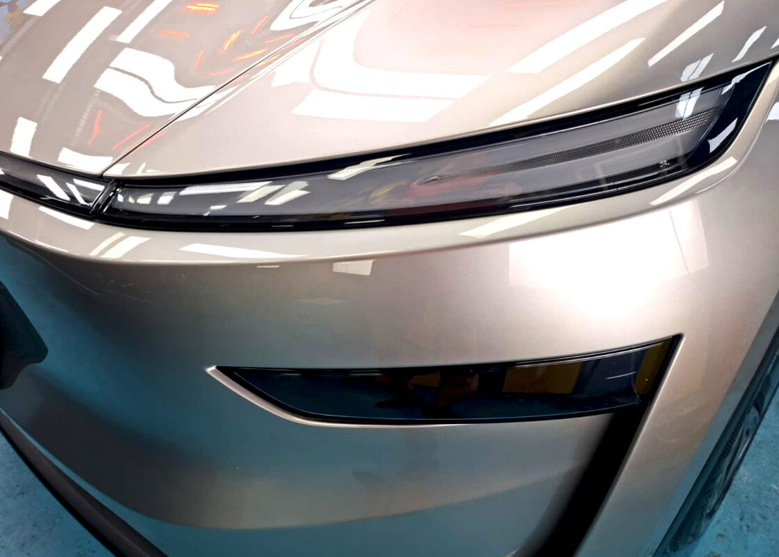 Close-up of the Tesla Model YL's headlight and hood, reflections crisp after coating.